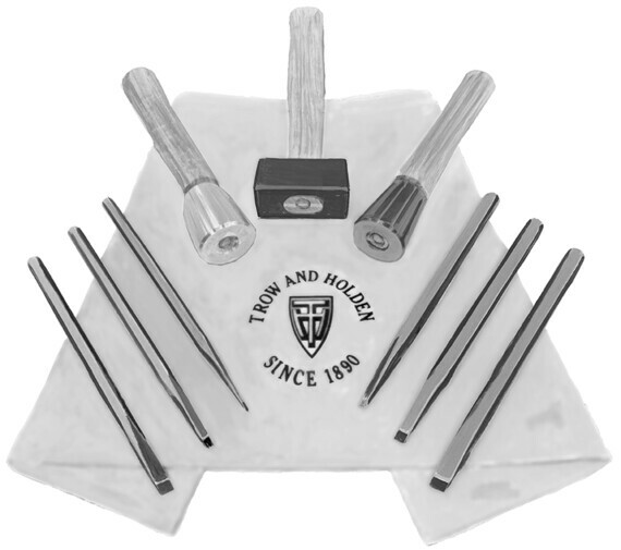 A collection of six carbide tipped chisels and a stone hammer for delicate carving laid out on a foldable carrying case